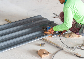 Worker cuts a metal sheet for installation on the roof of the godown.