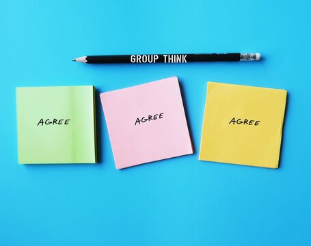 Notes on blue background with words AGREE concept of Groupthink -  phenomenon occurs when group reaches consensus without critical reasoning or evaluation but based on common desire not to upset group