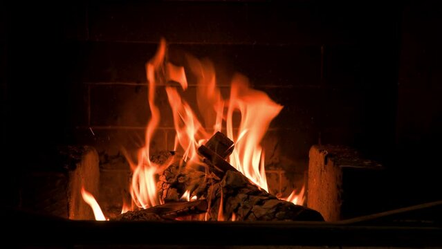 Home fireplace with red flame and firewood. 4K video relaxing endless footage