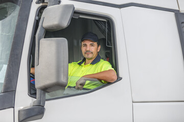 Confident male driver sitting in white truck and looking at camera