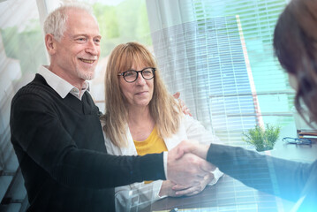 Female realtor giving handshake to happy senior couple after successful agreement; multiple exposure