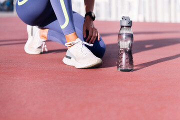feet with running shoes of an unrecognizable female runner next to her water bottle, concept of...