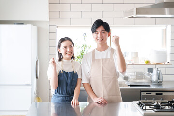 キッチンでガッツポーズする夫婦（料理・家事） © polkadot