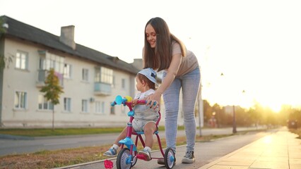 mother teaches daughter to ride. happy family kids dream concept. young mother teaches her daughter...