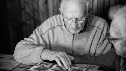 An elderly couple scrolls photos on a family album at home