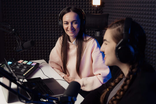 Two happy podcast hosts share a light-hearted moment, laughing together during a podcast recording in a soundproof studio