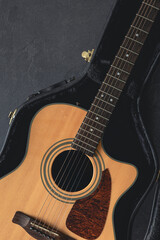 Fototapeta premium Acoustic guitar in a protective case on a dark background, top view.