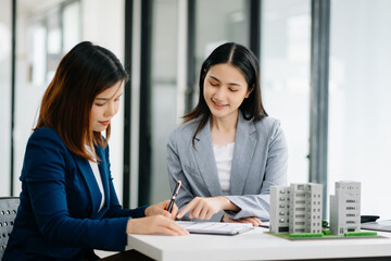 Real estate broker agent presenting and consult to customer to decision making sign insurance form agreement, home model, concerning mortgage loan offer.