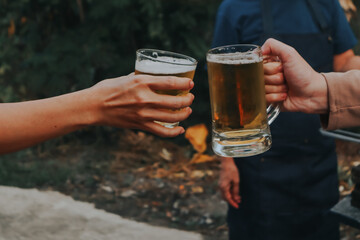 two hands holding frosty mugs of beer, one full and one half-empty, during what appears to be a...