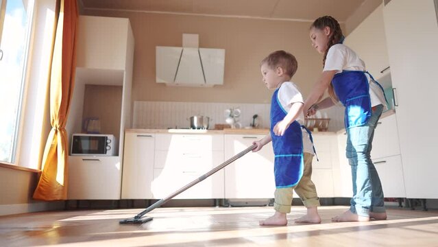 group of children baby washes the floors. happy family kid dream concept. group children washes the floors with a mop in the kitchen in an apron helps mom. mom asked the child to mop indoors