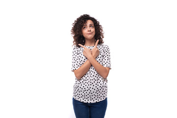 charming kind young brunette curly woman dressed in a summer blouse with a pea print actively gesticulates