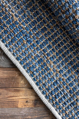 Hand woven geometric denim area rug on wooden floor.