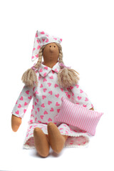 Funny handmade doll in pajamas dress holding pillow on white. Toy maded pink  color natural cotton linen material