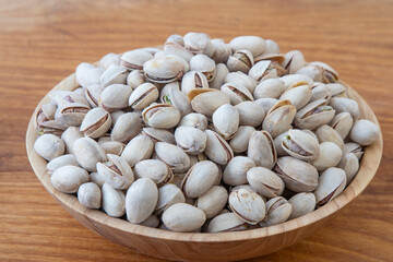 Pistachios in a wooden bowl. Wooden background. Healthy food