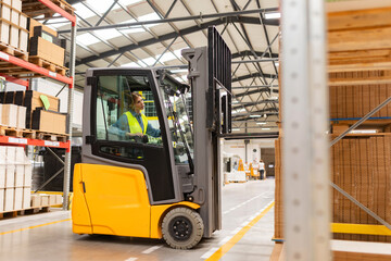 Female warehouse worker driving forklift. Warehouse worker preparing products for shipmennt,...