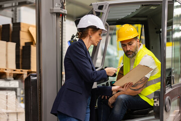 Forklift driver talking with manager in modern industrial factory. Warehouseman reading order, order picking. Warehouse worker preparing products for shipmennt, delivery, checking stock in warehouse. - obrazy, fototapety, plakaty