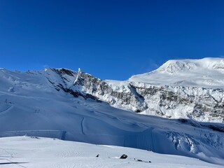 snowy mountain tops against dark blue ski from piz allalin saas fee valails wallis switzerland...