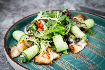 salad with arugula, lettuce, cucumber rolls, fish and sesame seeds, top view