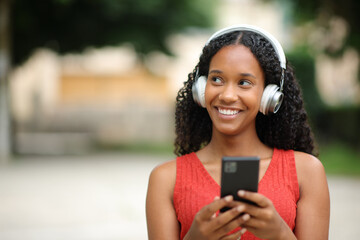 Happy black woman looks at side listening to music