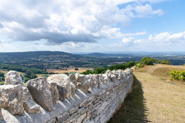 Close up view of a typical dry-stone wall in the Cotswolds on top of Crickley Hill, Gloucester, UK with panoramic view on the valley and outskirts of the greater Witcombe area