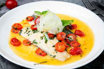 unpeeled fish with gravy, herbs, cherry tomatoes and onions, top view