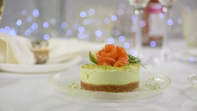 Timbale appetizer made from avocado, whipped with soft cheese cream and lime on short crust pastry with salmon. A great option for a holiday menu.