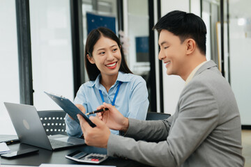 Young attractive Asian male office worker business suits smiling at camera in office .
