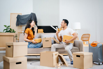 Asian young attractive couple man and woman use tablet and smartphone online shopping furniture decorate house with carton package move in new house. Young married asian moving home. . - obrazy, fototapety, plakaty