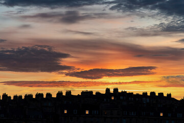 Low angle view of long row of characteristic townhouses with roofs and chimneys of Georgian houses in Bath, Sommerset, UK during sunset or dusk giving a dark silhouette