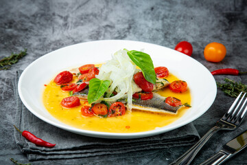 unpeeled fish with gravy, herbs, cherry tomatoes and onions, top view