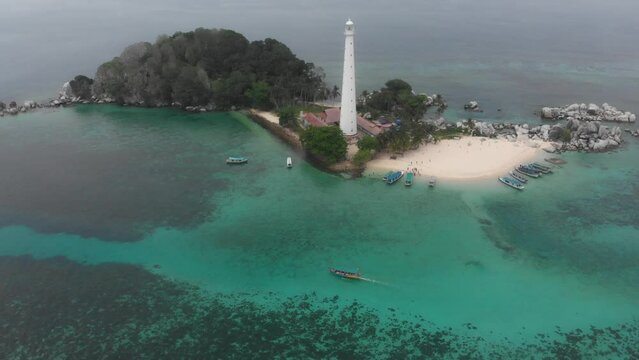 Reveal shot of Lengkuas Island Belitung with lighthouse and boat, aerial