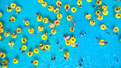 Top view of People relaxing in the pool on yellow inflatable circles