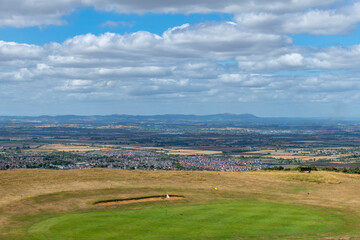 High angle view of green with flag of golf course high on a hill along public footpath Cotswolds...