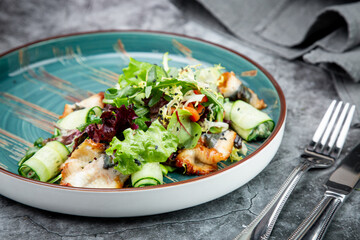 salad with arugula, lettuce, cucumber rolls, fish and sesame seeds, top view