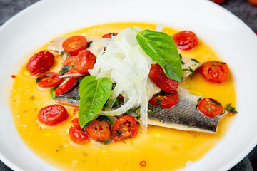 unpeeled fish with gravy, herbs, cherry tomatoes and onions, top view