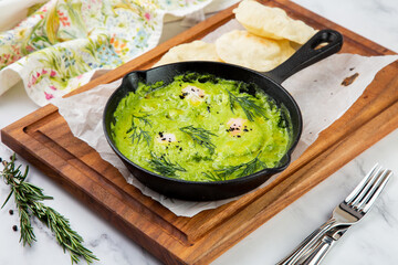 broccoli cream soup with herbs, cheese and tortillas in a frying pan, top view