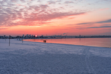 Beautiful sunset on the coast in winter. White snow lies on the embankment. Winter city beach....