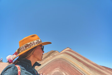 Woman standing in the rainbow mountain in Peru with all the colors of the mountain in the background.