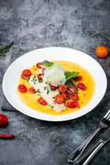 unpeeled fish with gravy, herbs, cherry tomatoes and onions, top view