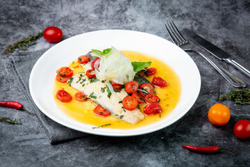 unpeeled fish with gravy, herbs, cherry tomatoes and onions, top view