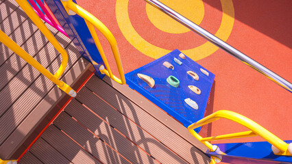 Sunlight and shadow on fiber walkway of climbing playground equipment with jungle gym on safety rubber floor in outdoors playground area at kindergarten, view from above