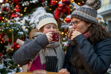 Two Friends Enjoying Red Glühwein by the Christmas Tree