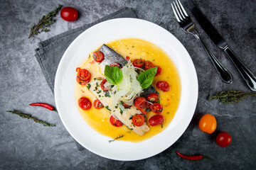 unpeeled fish with gravy, herbs, cherry tomatoes and onions, top view