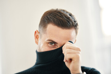 Handsome smiling man hiding behind turtleneck.