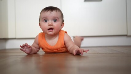 The child lies on the floor in the kitchen looks surprised. family happy childhood. family happy...