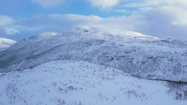Background of snow covered mountain hills and blue sky on a sunny winter frosty day. 4k aerial drone traking view