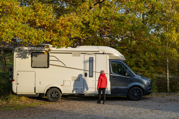 Naklejka premium Caravan travel trailer RV motor home camper. Car vehicle journey. Tourism Summer vacation holidays activity trip to Europe. A woman gets into a car for travelling. House on wheels concept.