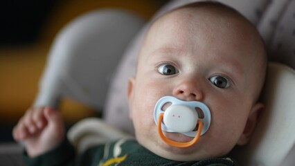 baby infant with pacifier. happy family kid dream concept. baby son sitting in a highchair with a...