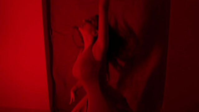 Stunning red light performance by a beautiful female dancer alone in a room