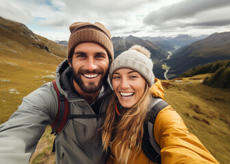 Cute couple of young people smiling and enjoying vacations trip together walking and trekking in mountains. Cheerful man and woman in love taking selfie